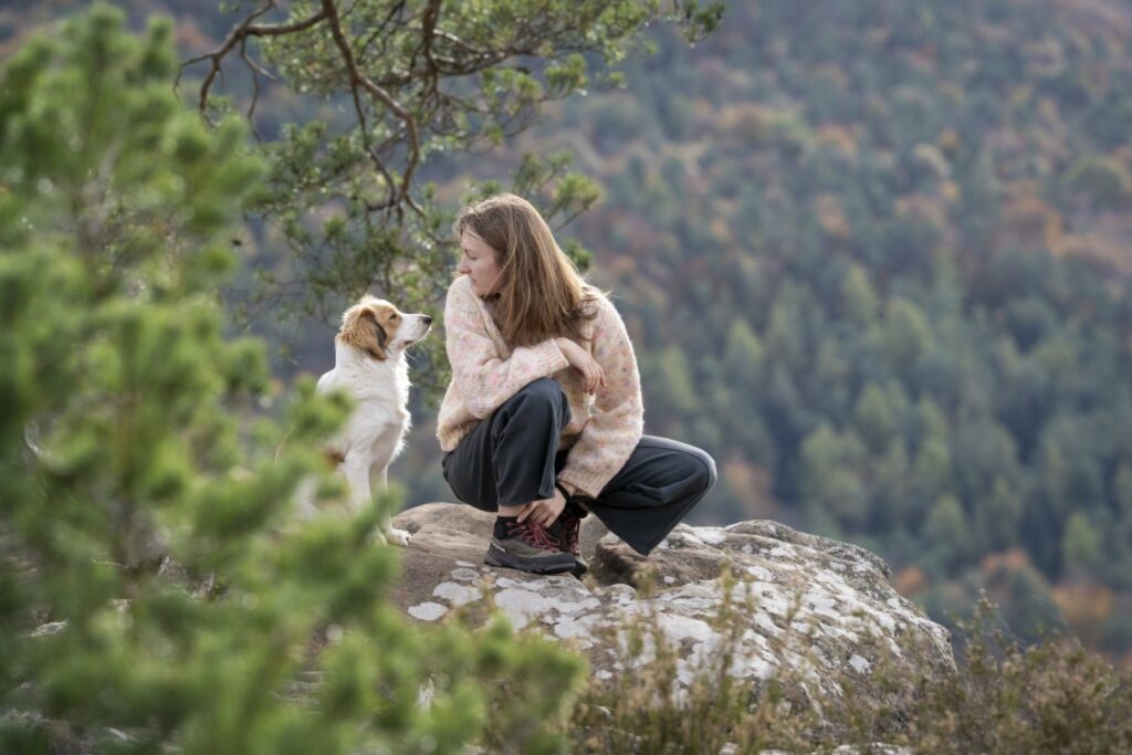 Cliente assise avec son chien sur un rocher en pleine nature, avis Apicani